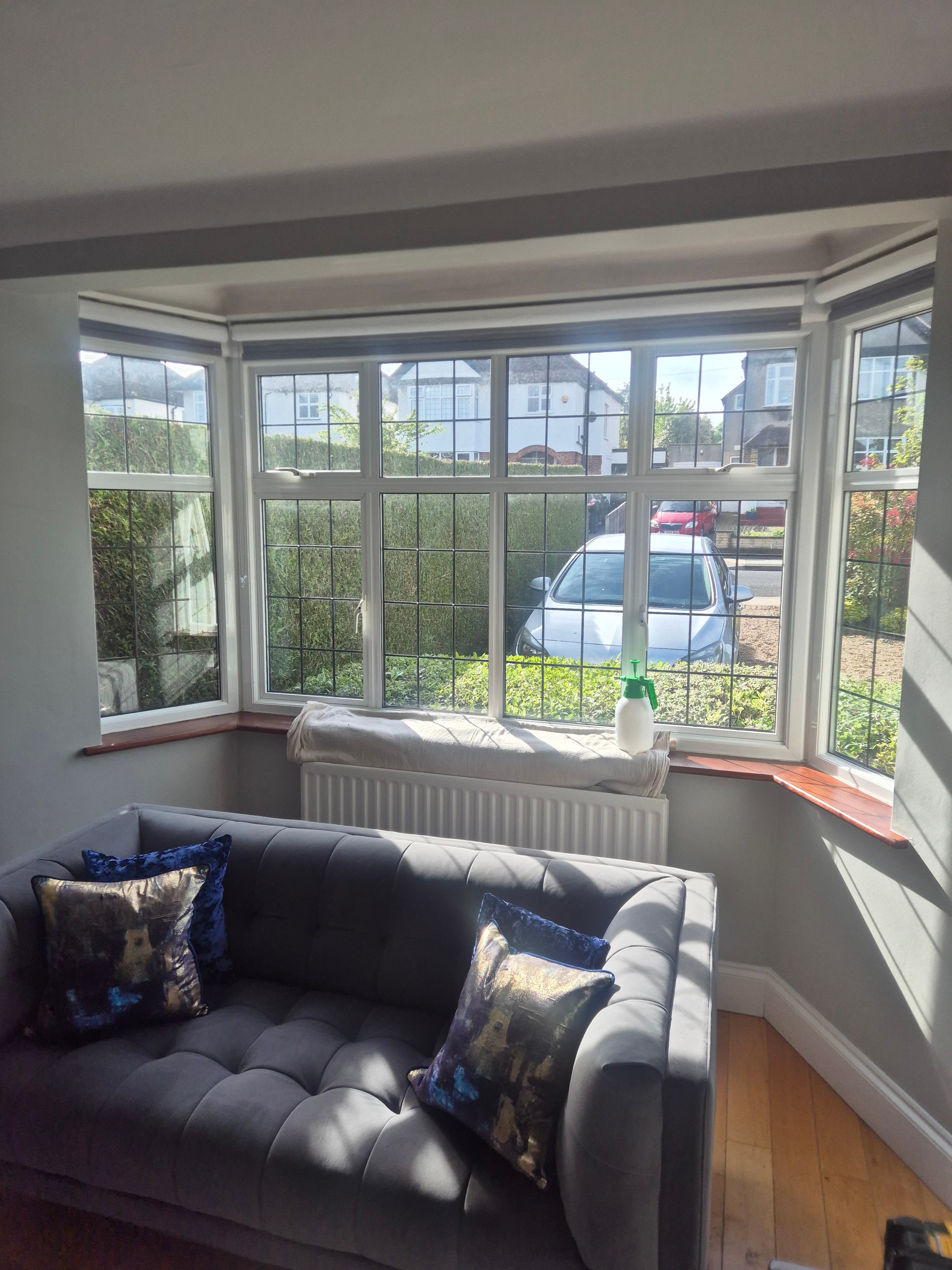 Interior view of a cozy living room bay window during installation by BucksTinting, showing bright natural light flooding the space