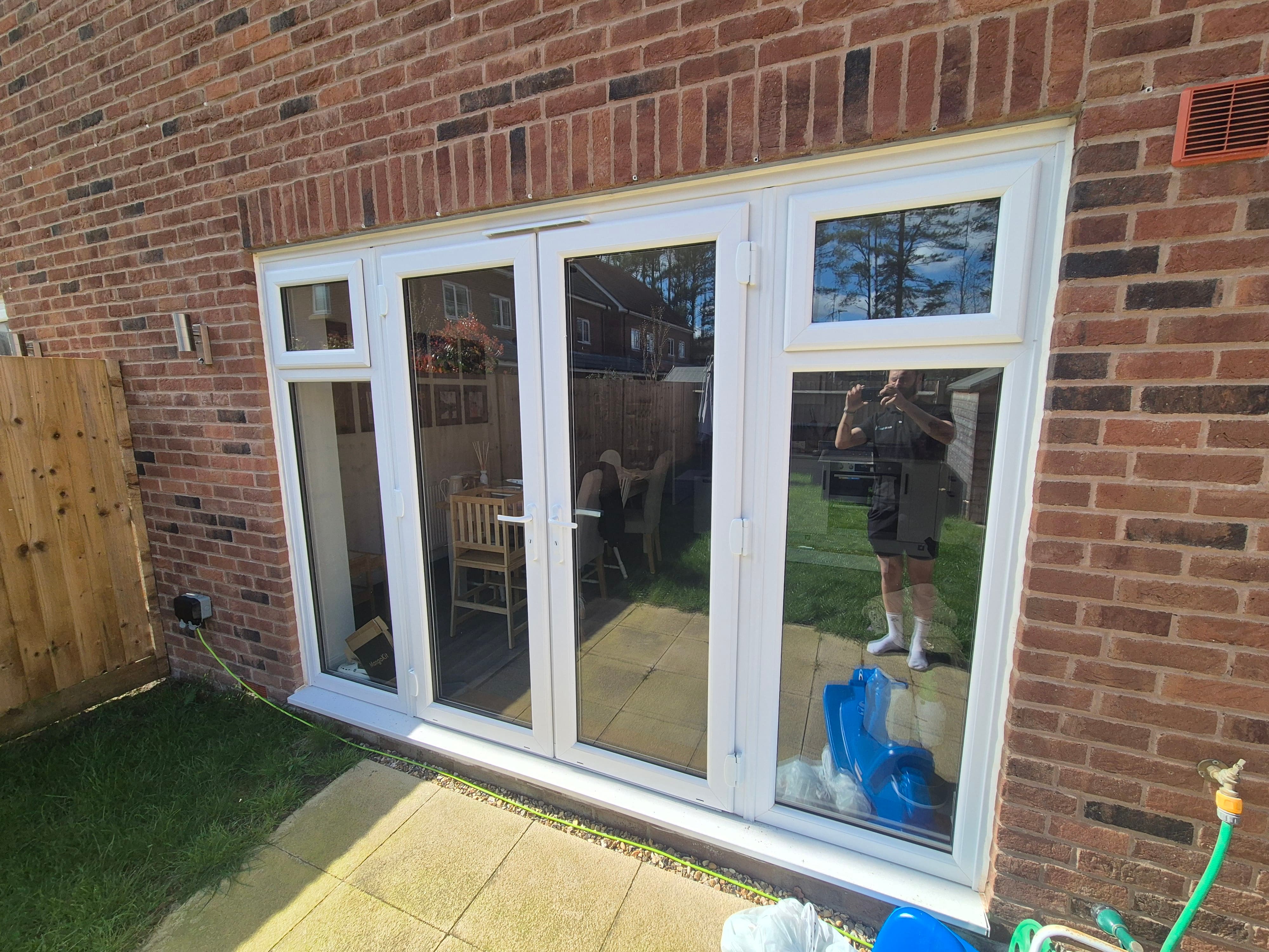 Untreated four‑pane bi‑fold doors in a Staines‑upon‑Thames home showing full interior visibility before window film installation, with no UV protection or heat control.